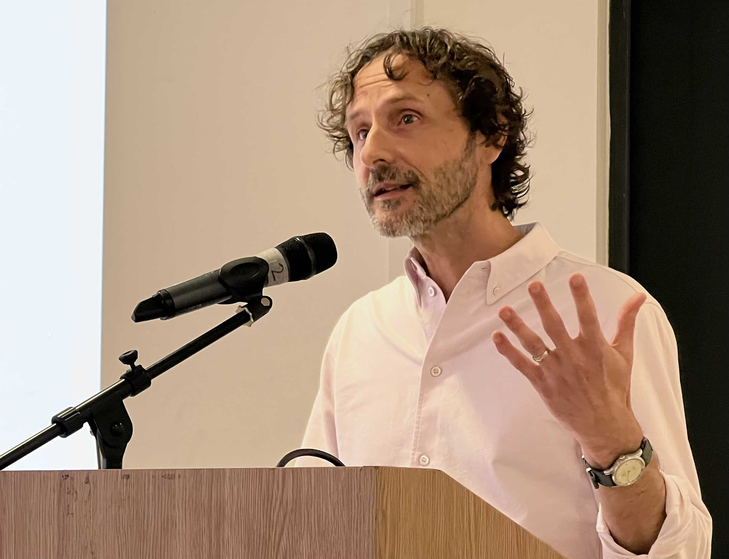 Alastair Lee presenting at a podium with microphone